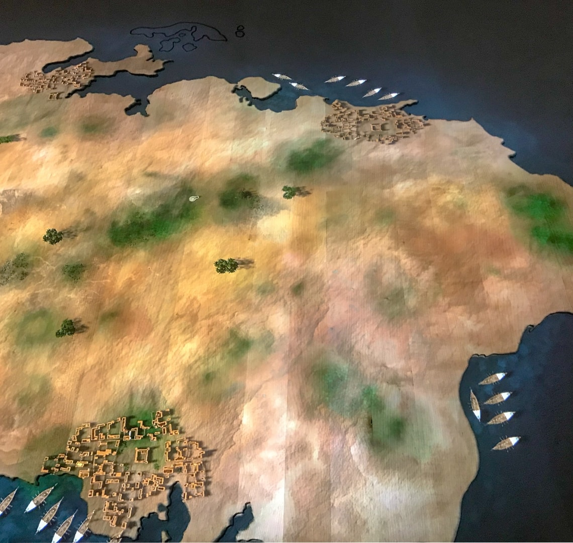 National Museum of Qatar - a digital map showing the annual migration patterns. There are green spots showing in teh arid desert and dhow boats docked at the coast.