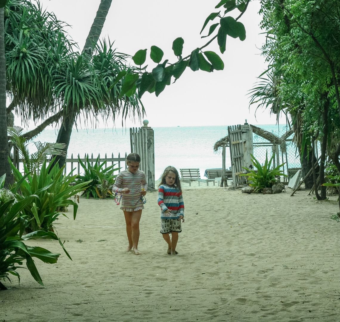 2 sisters walking up a sandy path among palm trees on Uppuveli Beach