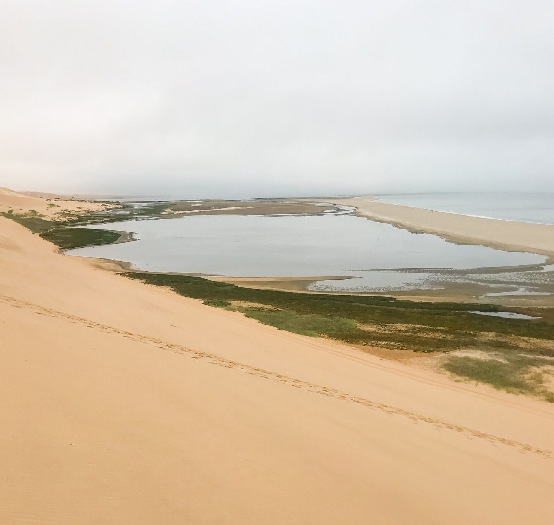 2 Week Namibia Itinerary - The sand dunes of Walvis Bay drop straight into the ocean in a very dramatic way. We climbed to the top and could see the sea lakes below us, then a sandbank and then the sea. 