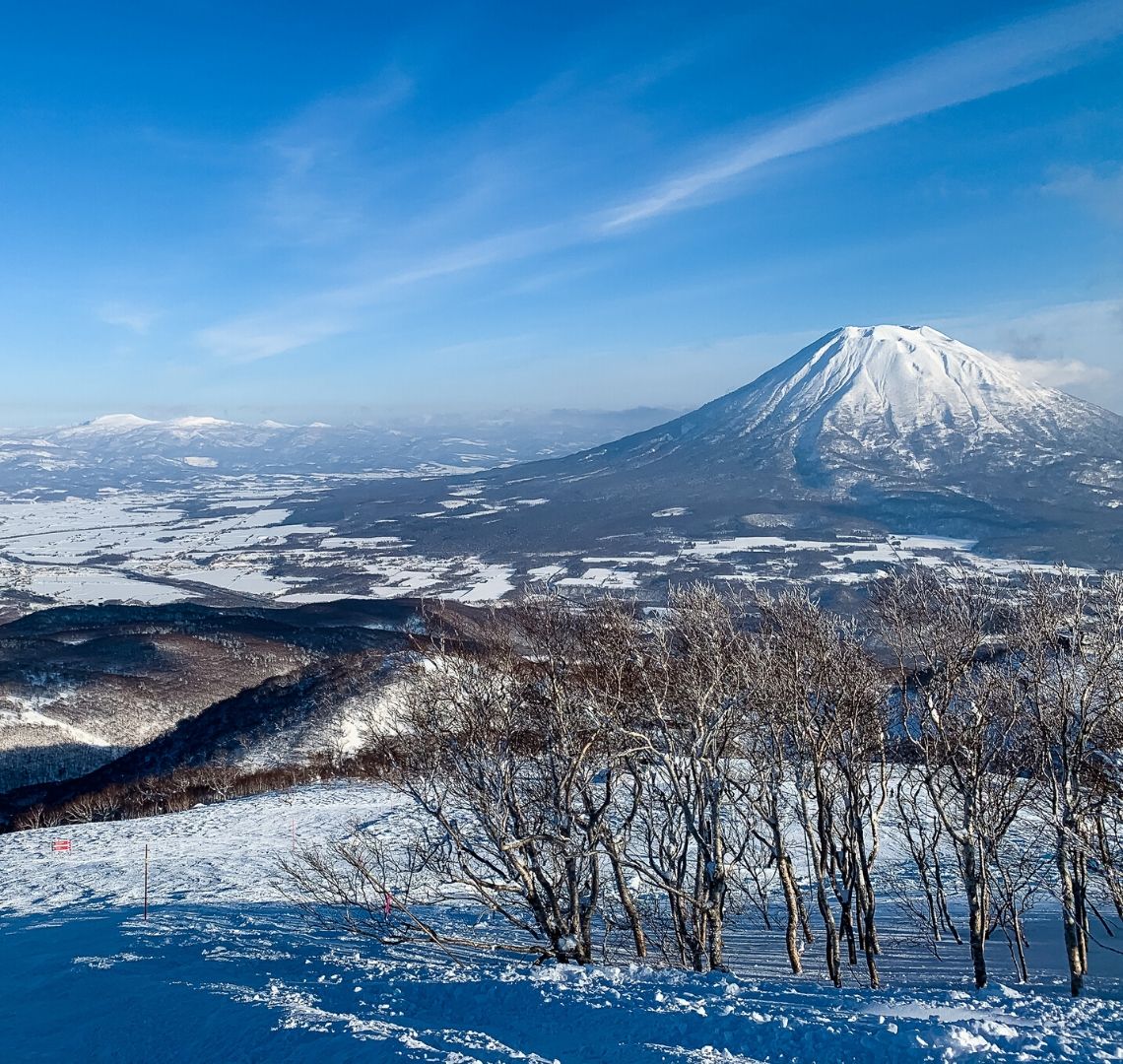 5 reasons to go family skiing in Niseko - Mount Fuji in the mid ground with other smaller mountains in the distance and trees in the foreground