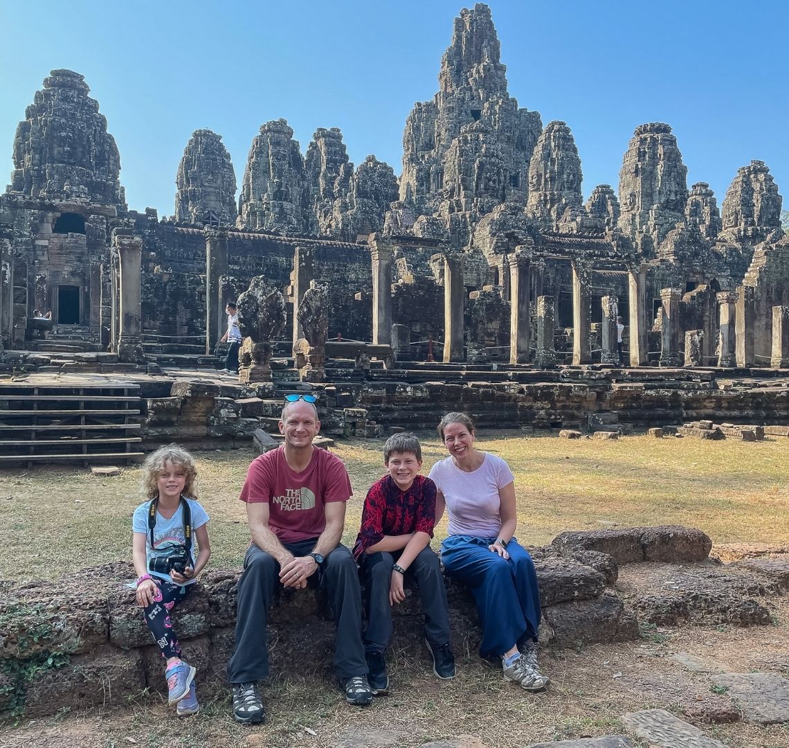 Thing2, Mr Wanderlust, Thing 1 and me sitting on a ruin wall in front of the ruins of Bayon temple